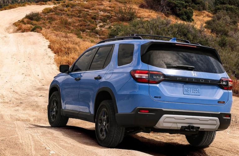 One blue color 2023 Honda Passport is running on a hilly road.