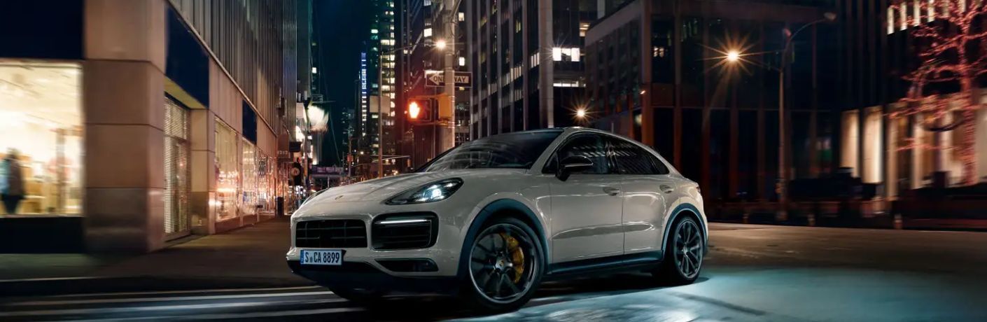 A 2023 Porsche Cayenne on a well-lit city road