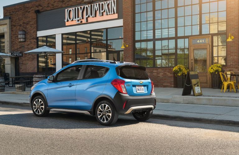 Angled rear view of the 2017 Chevrolet Spark parked near a shop