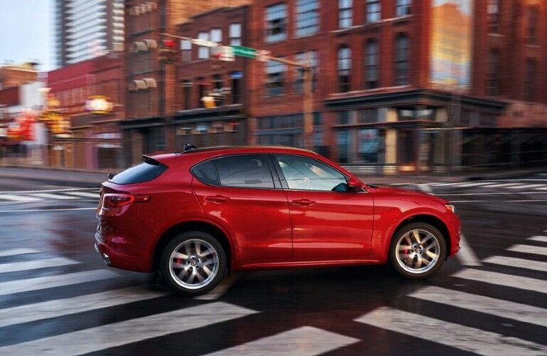 Passenger angle of a red 2020 Alfa Romeo Stelvio driving in a city