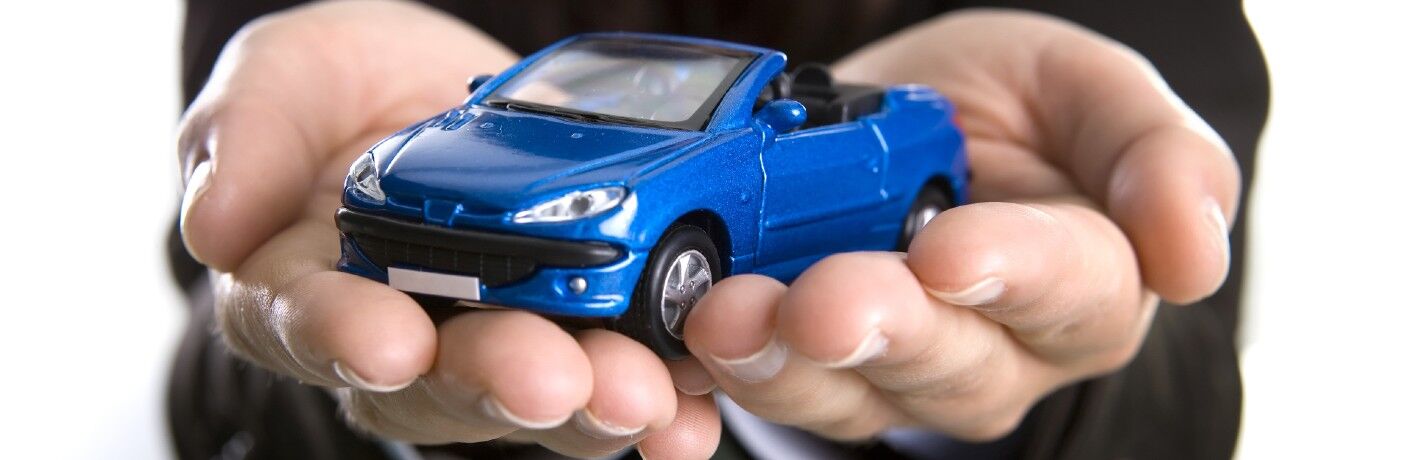 business person holding a blue toy car in their hands
