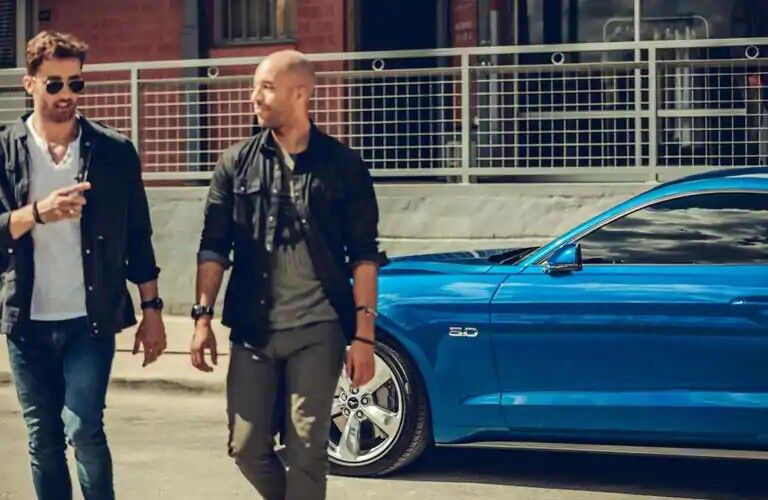 Two men walking alongside blue 2020 Ford Mustang GT