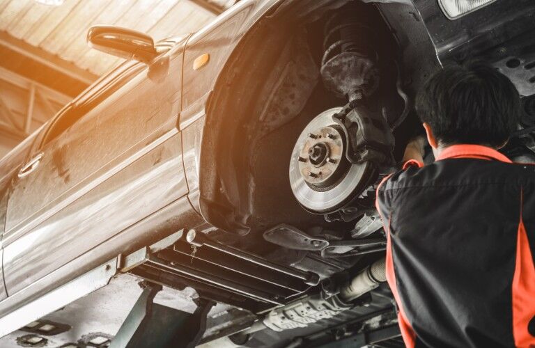 Mechanic working on the brakes of a car lifted into the air