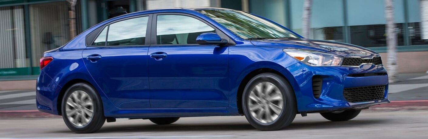 Exterior view of a blue 2019 Kia Rio driving down a city street