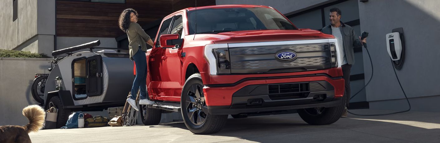 red 2025 Ford F-150 Lightning with a person hanging off the side