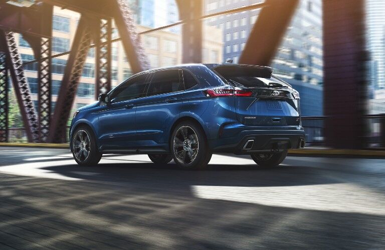 Rear driver angle of a blue 2020 Ford Edge driving on a bridge