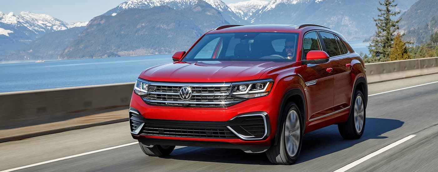 A red 2022 Volkswagen Atlas Cross Sport driving on an open road.