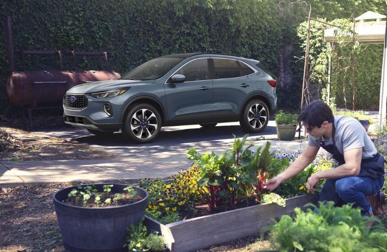 Side view of the 2023 Ford Escape with a man gardening in the background