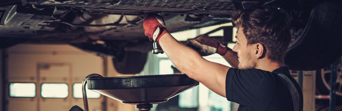 Car mechanic changing oil on car