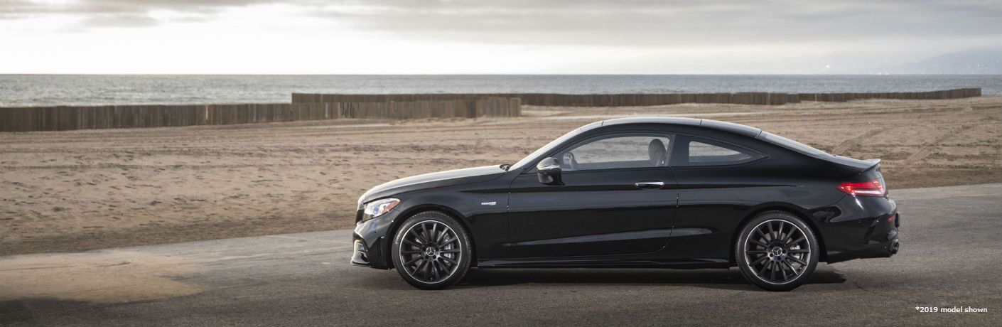 2020 MB AMG C 43 Coupe exterior driver side profile in empty lot with water behind fence