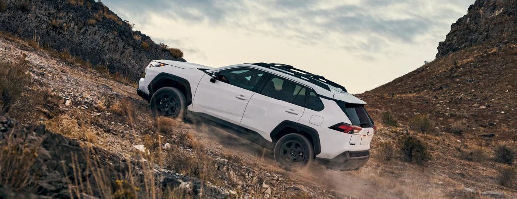 One white color Toyota RAV 4 is running on a hilly road.