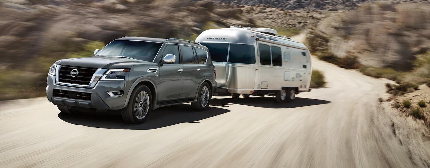 Grey 2023 Nissan Armada towing a silver camper trailer on a dirt road