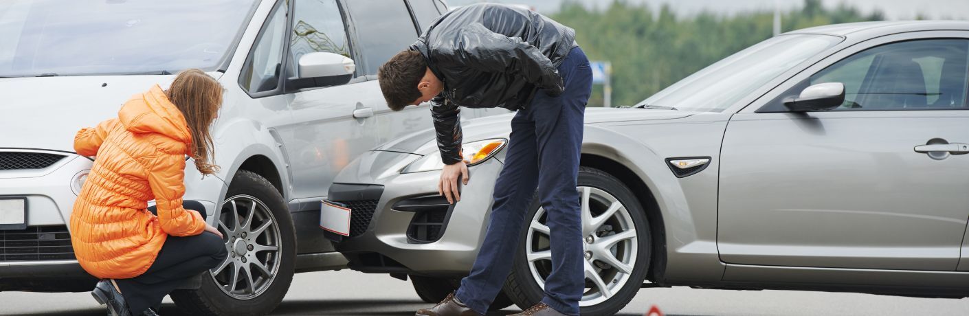 Two people checking the body of two cars in collision