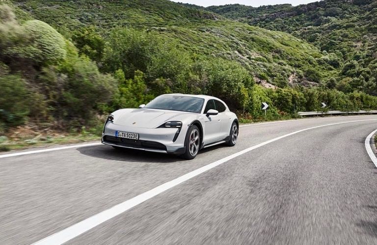 The 2021 Porsche Taycan Turbo S on the road against a lush green backdrop