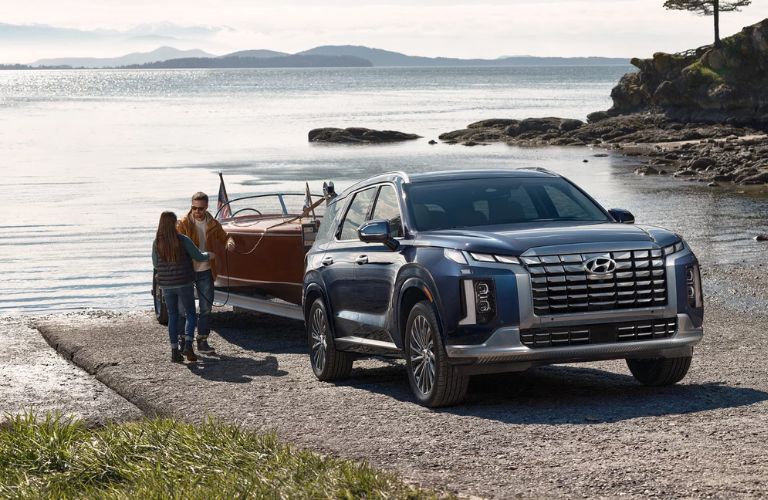 2024 Hyundai Palisade towing a boat with a couple in the foreground