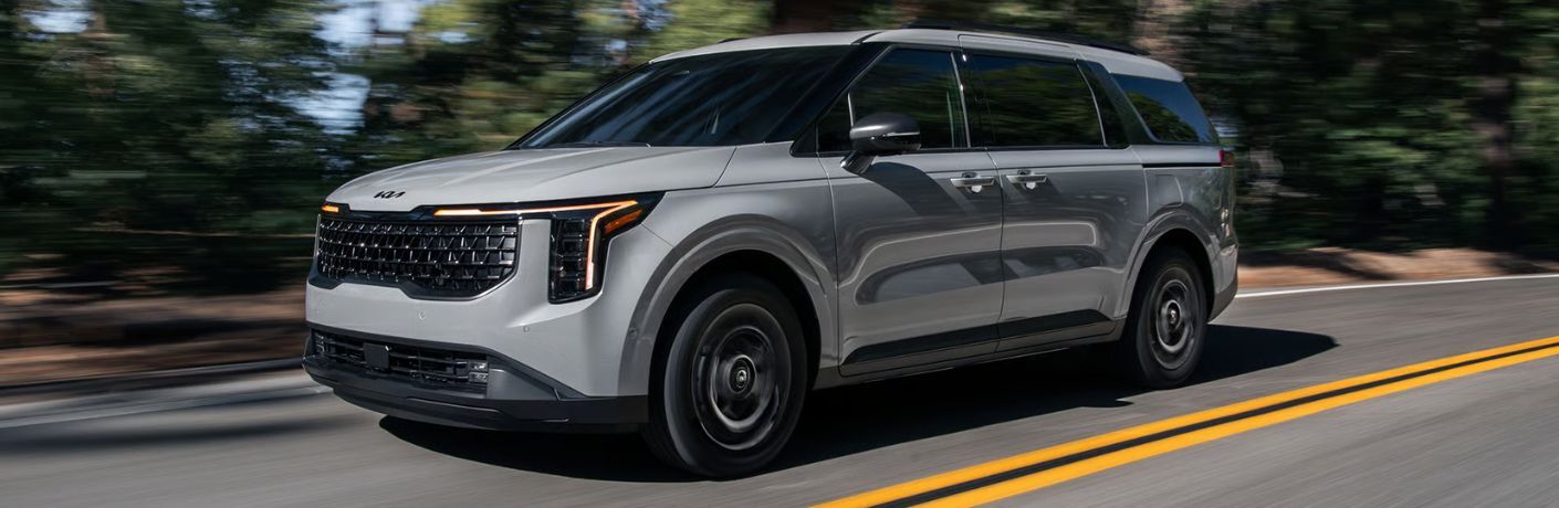 2026 Kia Carnival Hybrid on a road front and side view