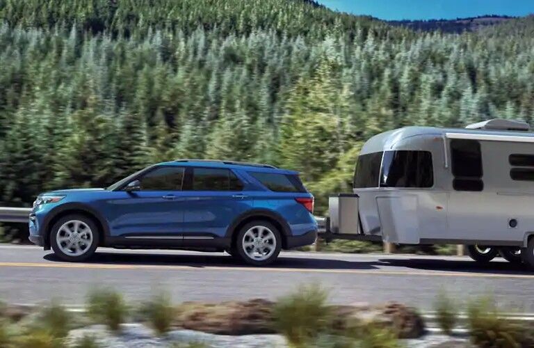 Blue 2020 Ford Explorer XLT towing trailer on wooded road