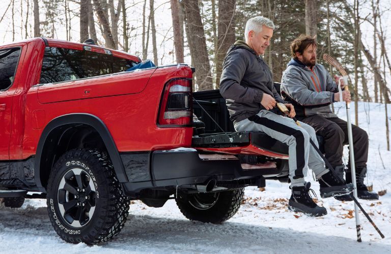 two men sitting on the tailgate of a 2019 Ram 1500 truck