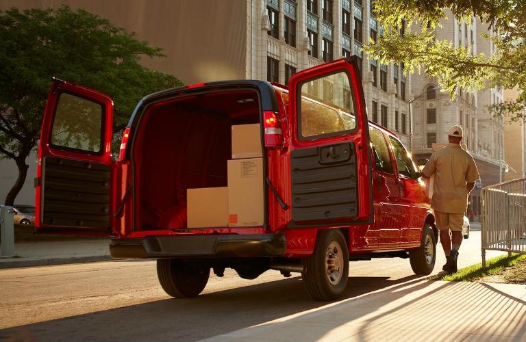 rear view of red 2018 chevrolet express cargo van with doors open and full of boxes