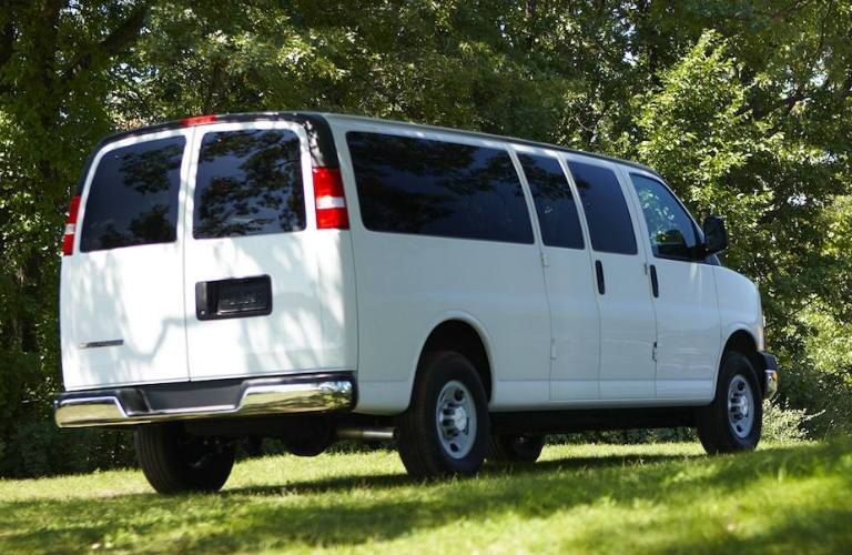 rear view of white 2018 chevrolet express cargo van on grass surrounded by trees