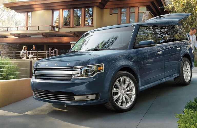 blue 2019 ford flex in driveway of home with liftgate open and people unloading luggage
