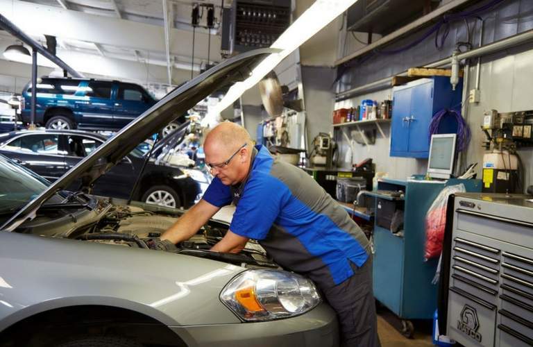 Broadway Automotive service technician employee working under the hood of a car