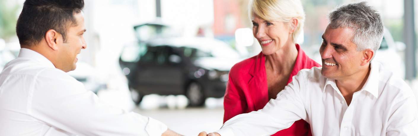 Couple Shaking Hands with Car Dealer After Signing Paperwork