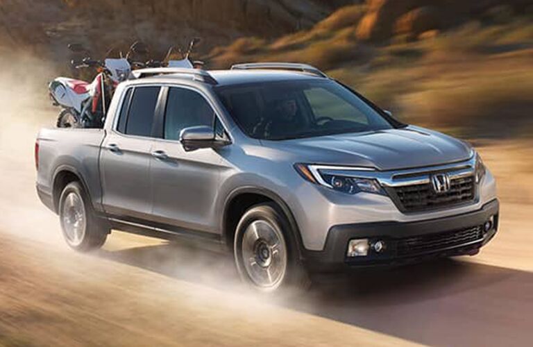 full view of the Honda Ridgeline driving off road with dirt bikes in the back