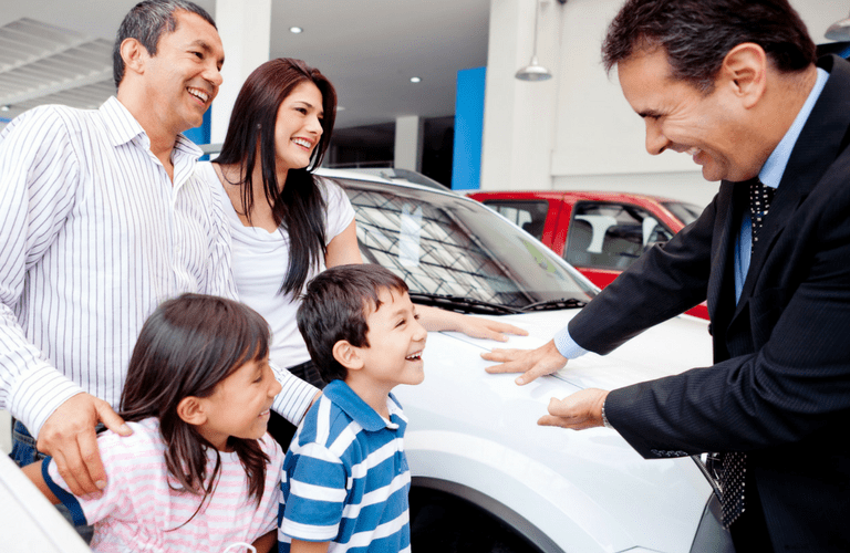 hispanic family talking to sales associate at car dealership
