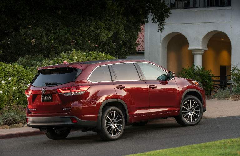 A right profile view of a red 2018 Toyota Highlander parked in front of a house