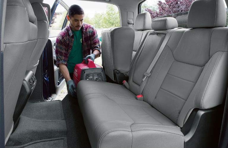 A young man places a piece of equipment in the back seat of the 2018 Tundra taking advantage of its flip-up seats