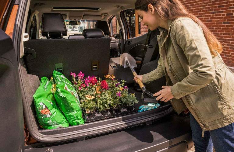 A photo of a young woman placing items in the back of the 2018 Ford EcoSport showing how versatile it is