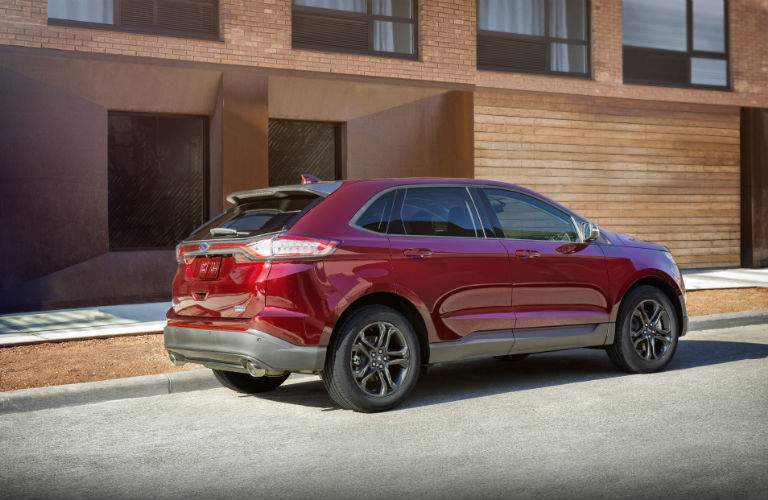 A right profile view of a red 2018 Ford Edge parked in front of an apartment building