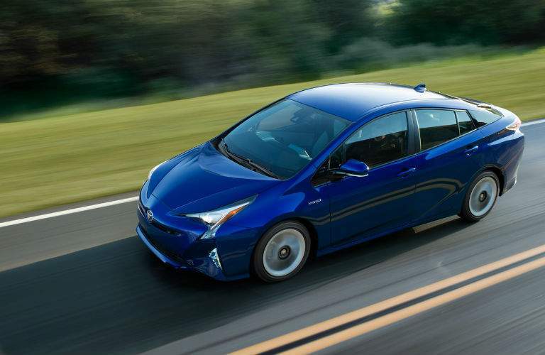 An overhead view of a blue 2018 Toyota Prius driving on a country road