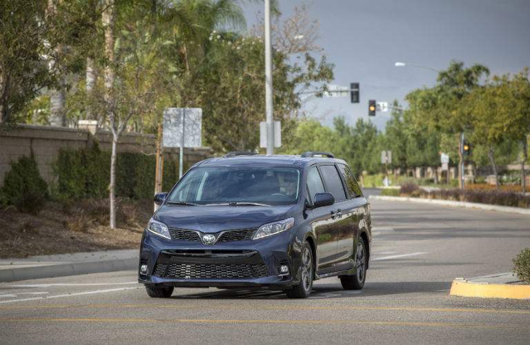 A front view of a blue 2018 Toyota Sienna driving down a city street