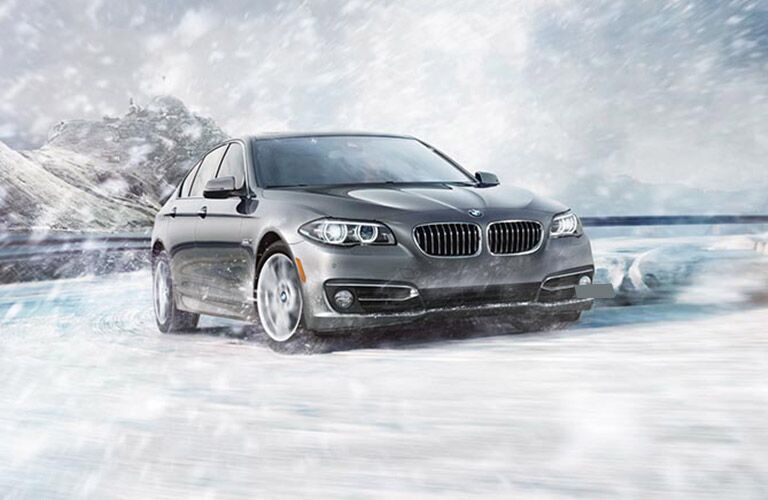 grey 2016 BMW 5 Series driving in the snow