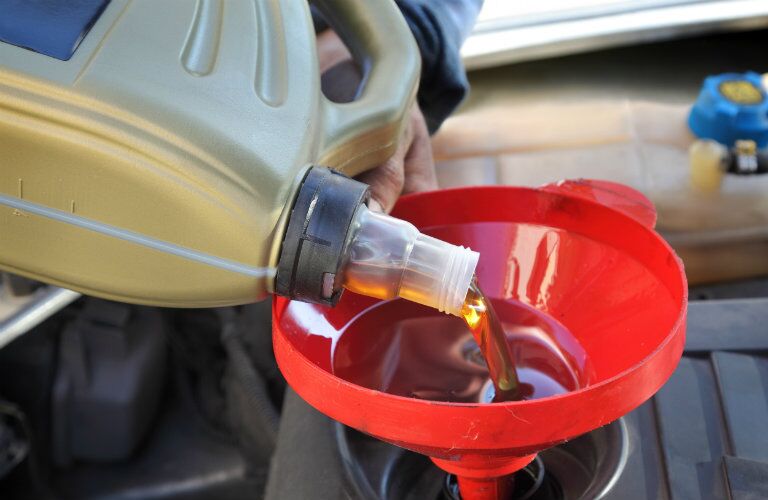 mechanic pouring oil into a vehicle