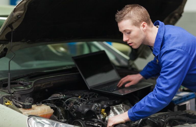 technician using computer to help check under car hood