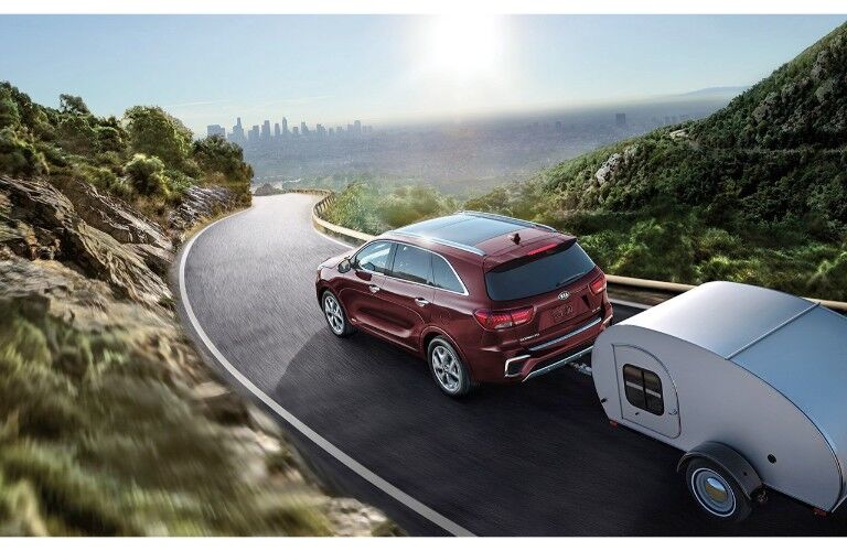 2019 Kia Sorento exterior overhead shot with red paint color towing a trailer through a grassy mountain hill path