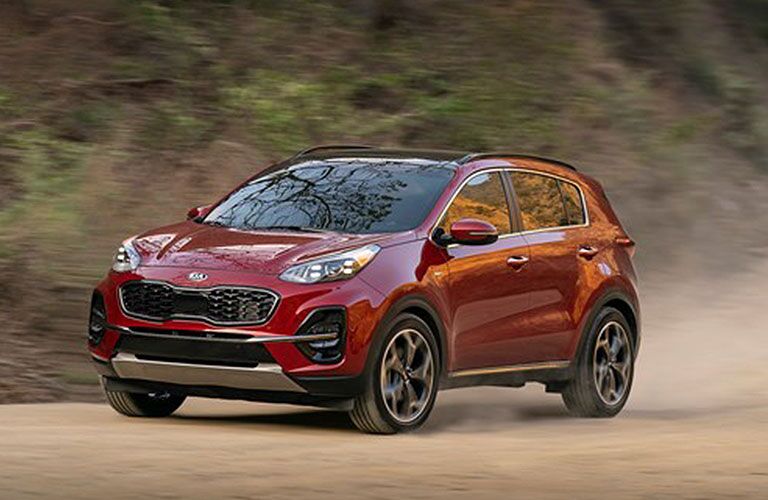 2020 Kia Sportage SUV redesign with red paint color parked on a dirt forest road