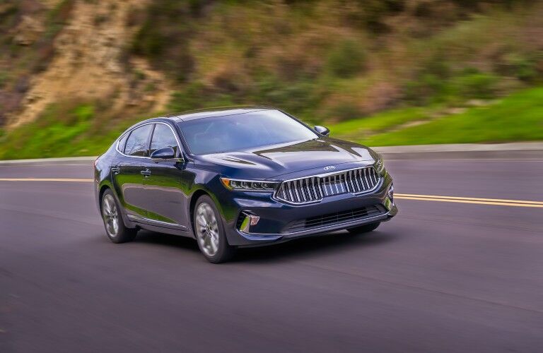 2020 Kia Cadenza exterior shot driving on a highway near a mountain cliff