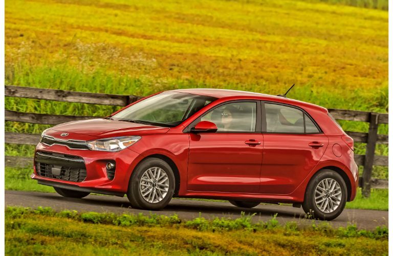 2020 Kia Rio 5-Door hatchback model in red exterior side shot parked near fields of grass