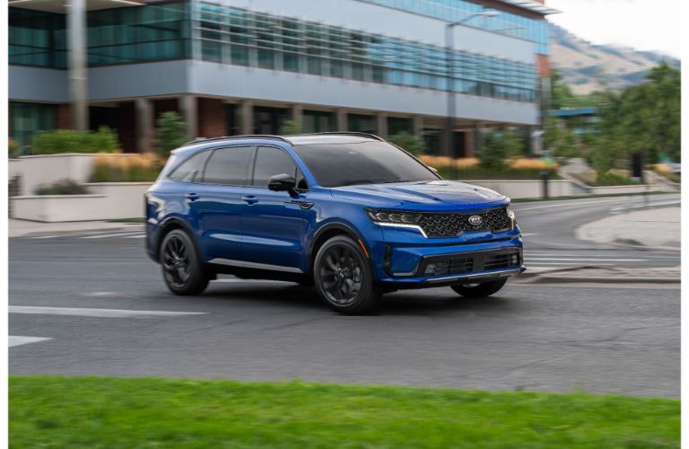 2021 Kia Sorento exterior shot with blue paint color driving past a building near a grass field