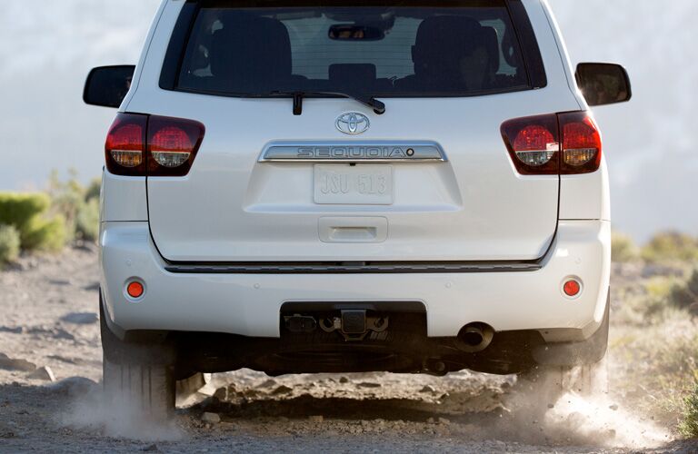 Rear Side of a White 2019 Toyota Sequoia Driving down a dirt road