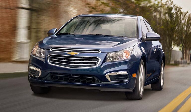 Blue Chevy Cruze driving past houses
