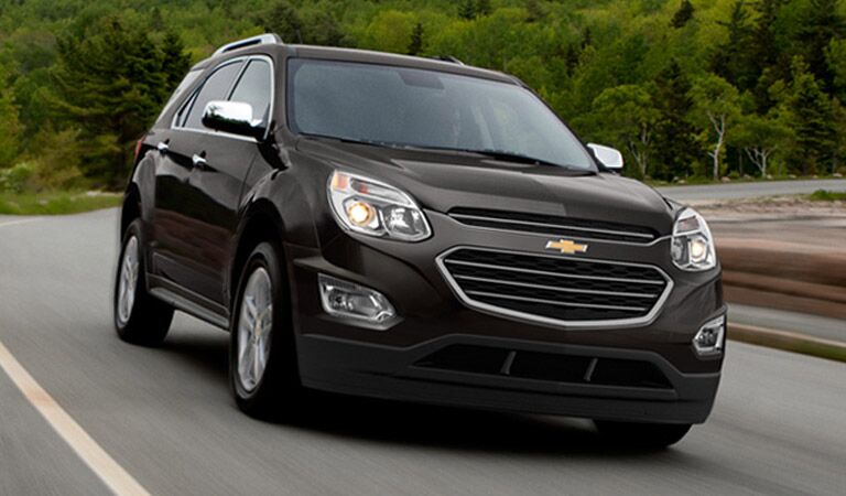 Black Chevy Equinox driving near the forest