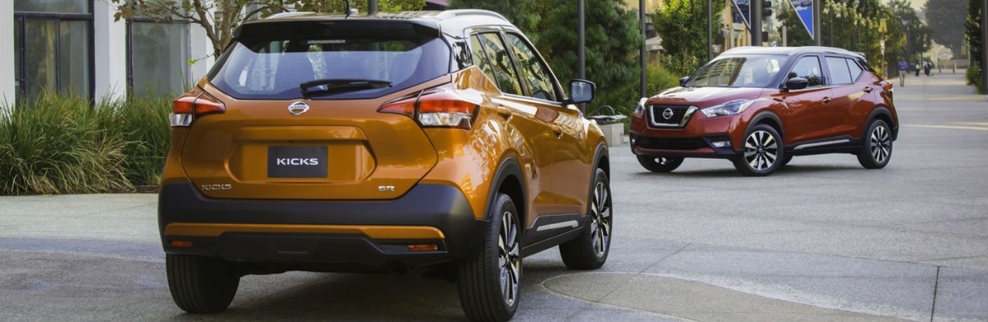A photo of two models of the 2018 Nissan Kicks parked on a street.