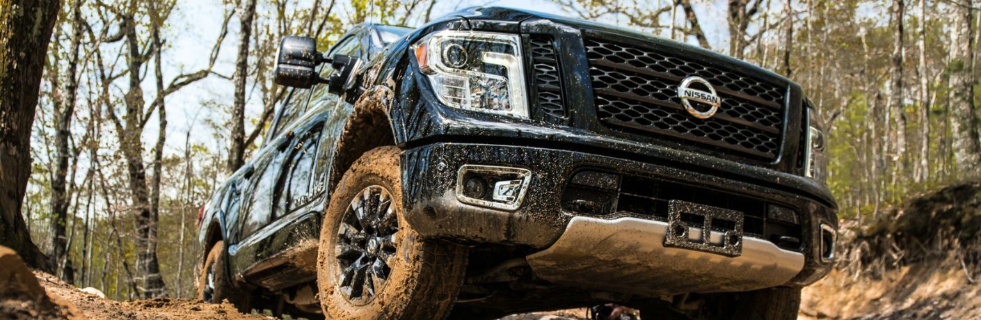 An upward-looking photo of the 2019 Nissan Titan coming over a muddy hill.