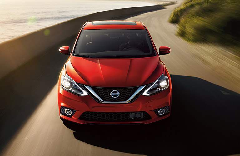 A full head-on view of a red 2018 Nissan Sentra on a road near the beach