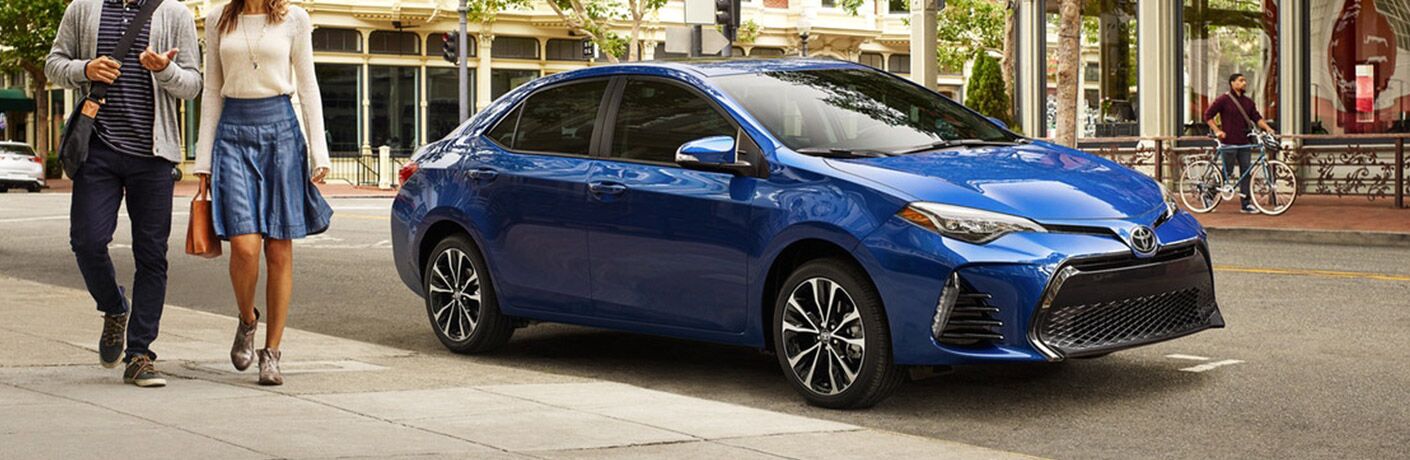 2019 Toyota Corolla exterior front fascia and passenger side parked with couple walking on sidewalk
